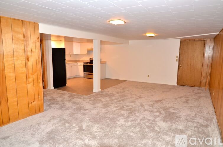 A spacious room with a kitchen area in the background.