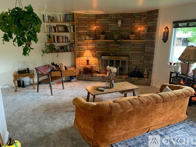A living room with a fireplace, a couch, and a potted plant.