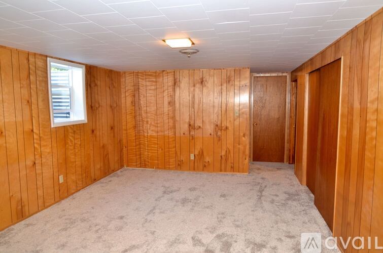 A room with wooden walls and a carpeted floor is available.