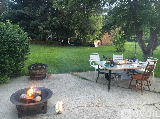 A fire pit with logs burning in it is in the middle of a gravel patio.