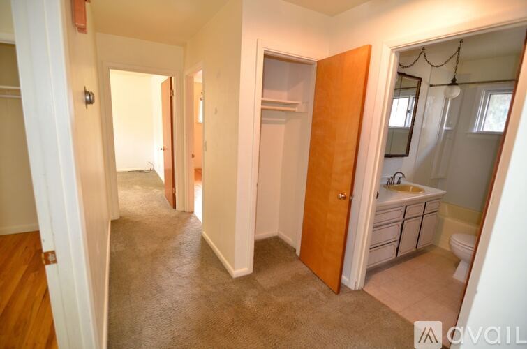 A hallway with a bathroom at the end.