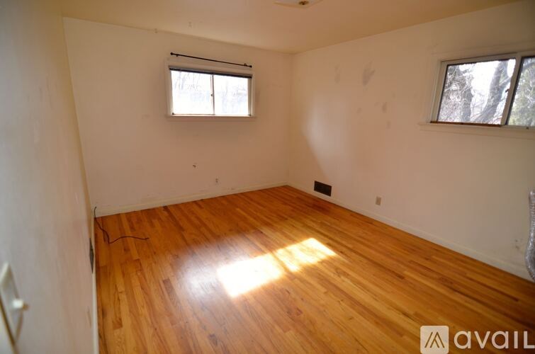 A room with wooden floors and two windows.