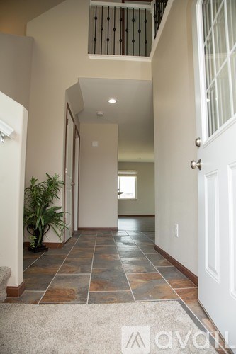 A hallway with a tiled floor and a white door.