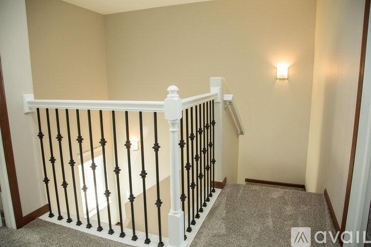A stairway with a white railing and a light on the wall.