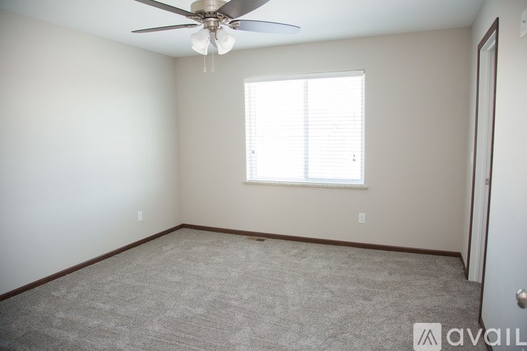 A room with a ceiling fan and a window with blinds.