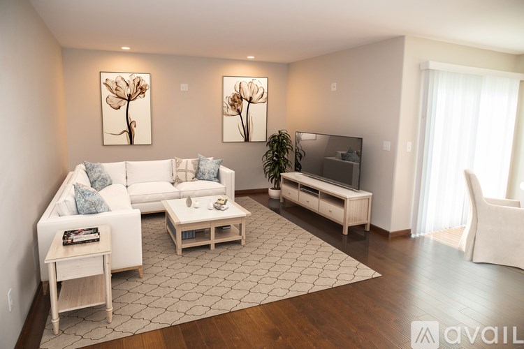 A living room with a white couch, a coffee table, and a TV.