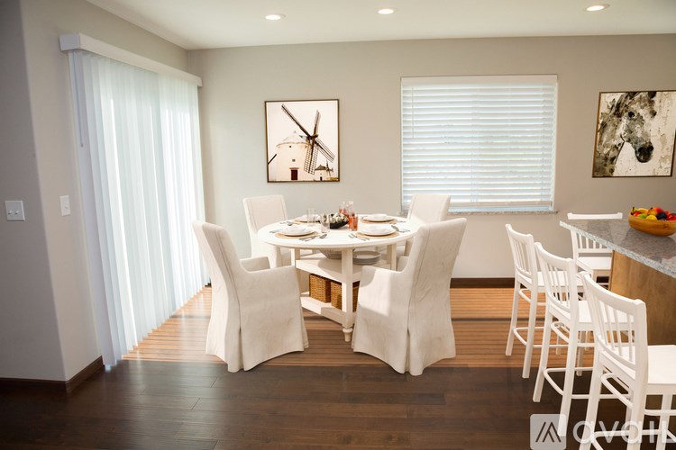 A dining room with a table set for four and a windmill picture on the wall.