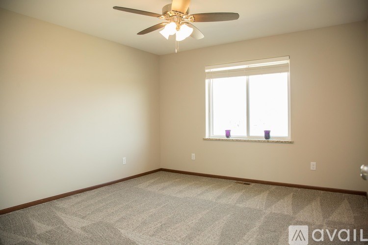 A room with a ceiling fan and a window with a view of the sky.