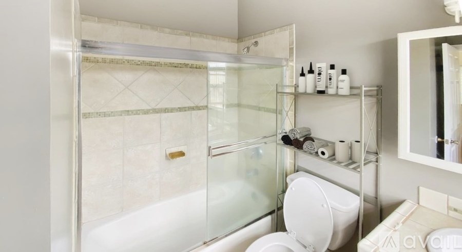 A white bathroom with a glass shower door and a white toilet.