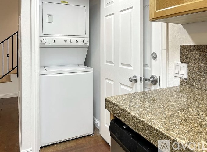 A white dishwasher is in a kitchen next to a white door.