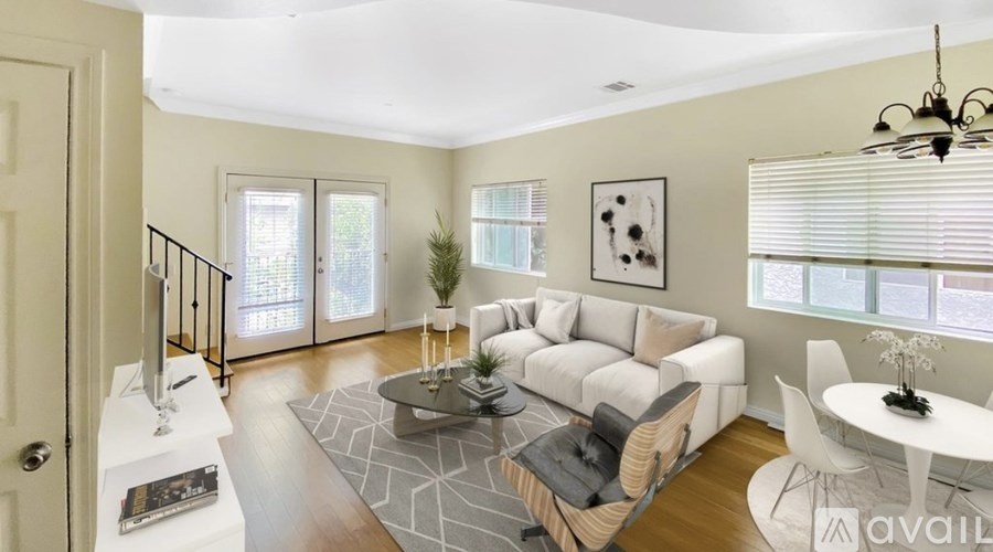 A living room with a white couch, a coffee table, and a chandelier.