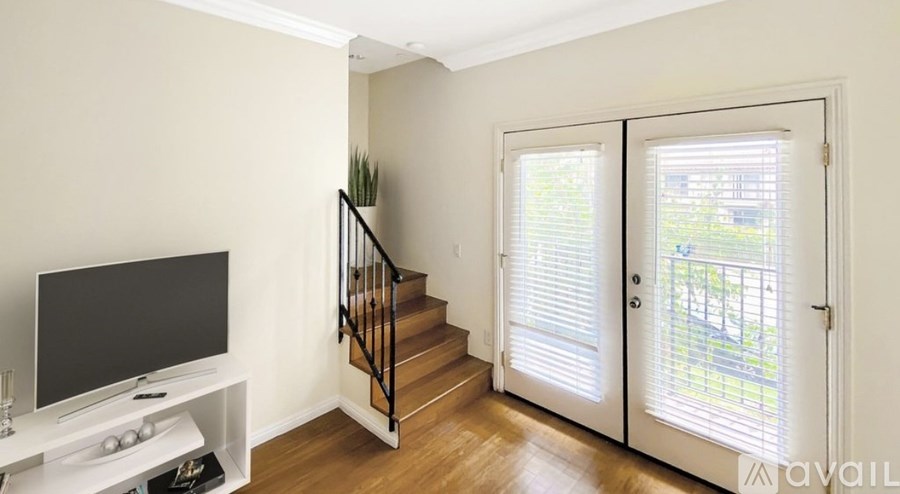 A living room with a television, a staircase, and a sliding glass door.