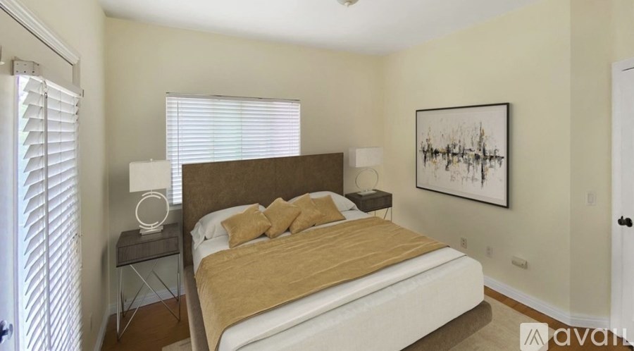 A bedroom with a bed, nightstand, and a painting on the wall.