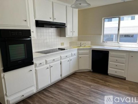 A kitchen with white cabinets and a black oven.