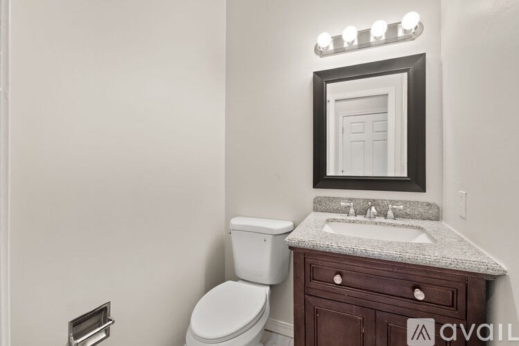 A bathroom with a toilet, sink, and mirror.