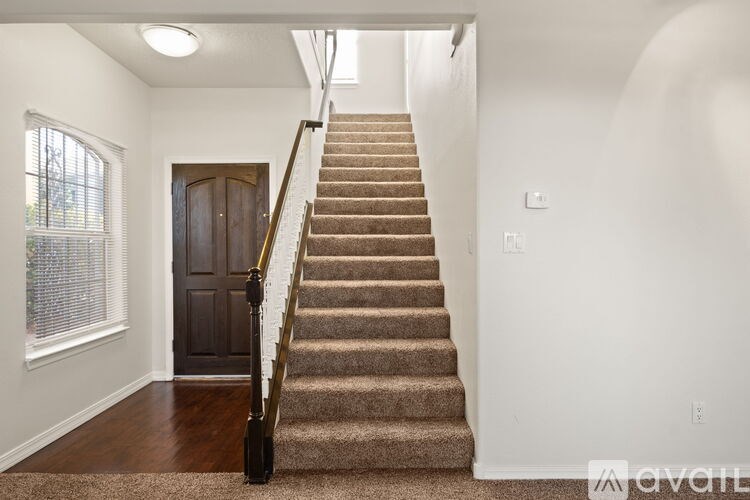 A staircase with a carpeted runner and wooden handrail.