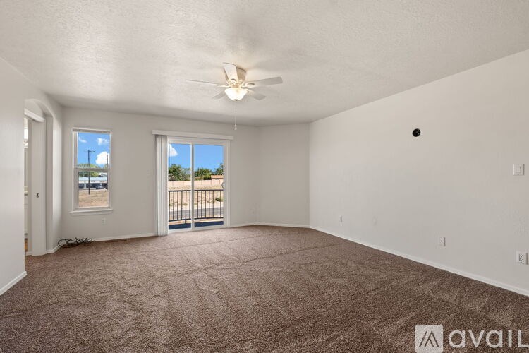 A room with a carpeted floor and a ceiling fan.