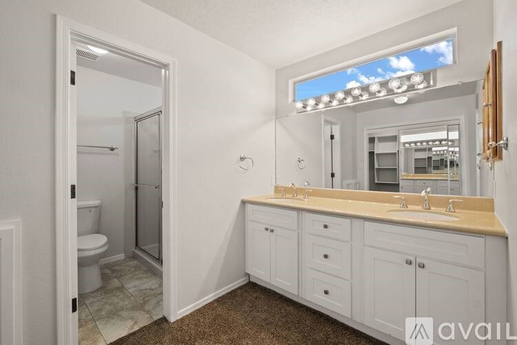 A bathroom with a toilet, sink, and mirror.