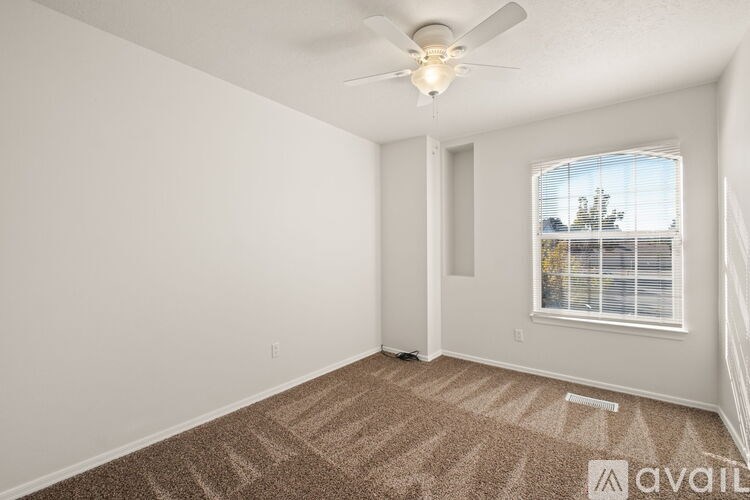 A room with a ceiling fan and a window with blinds.