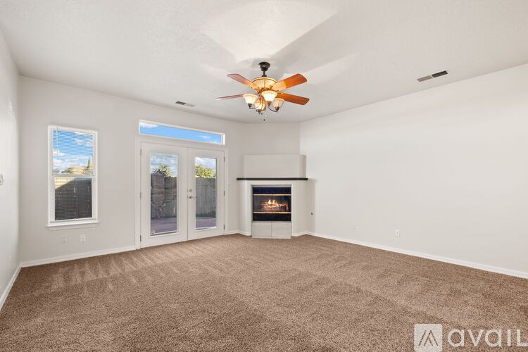 A spacious living room with a fireplace and a ceiling fan.