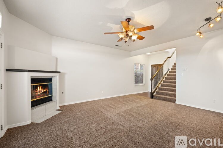 A spacious living room with a fireplace and a staircase.