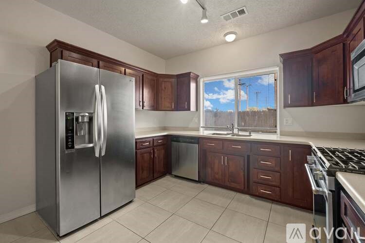 A kitchen with a stainless steel refrigerator and wooden cabinets.
