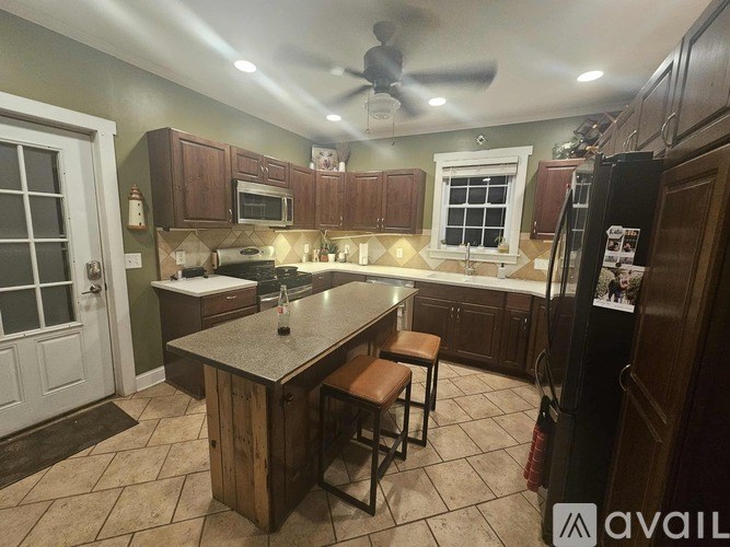 A kitchen with a wooden island and a ceiling fan.