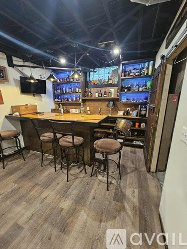 A bar with a wooden floor and a counter with stools.