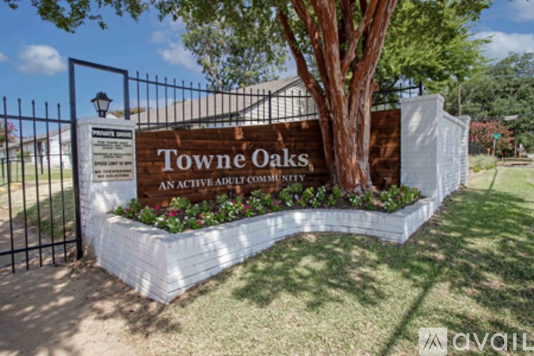 A sign that says Towne Oaks in front of a tree.