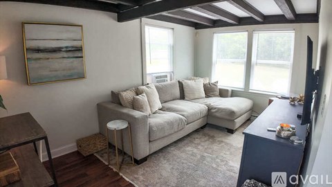 A living room with a grey couch and a painting on the wall.