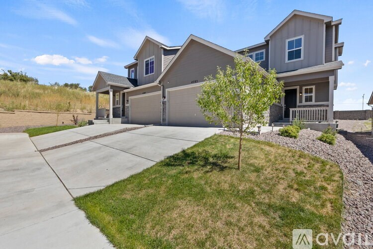 A house with a driveway and a tree in front of it.