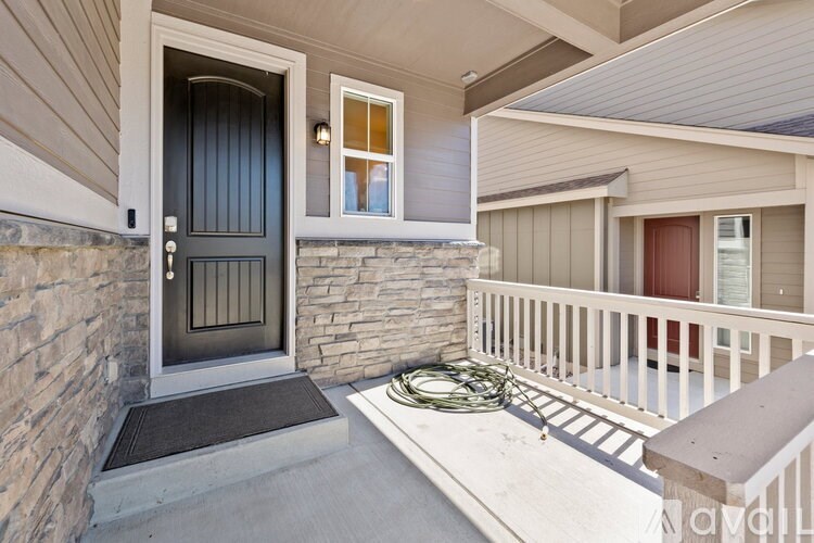 A house entrance with a black door and a stone wall.