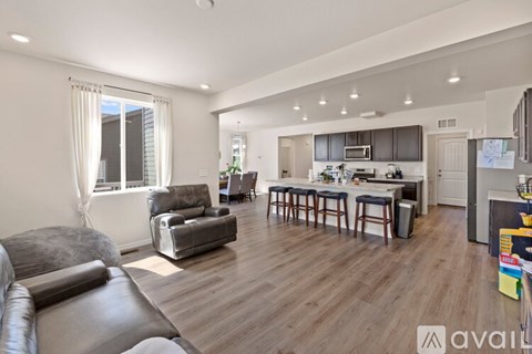 A living room with a grey couch and a kitchen in the background.