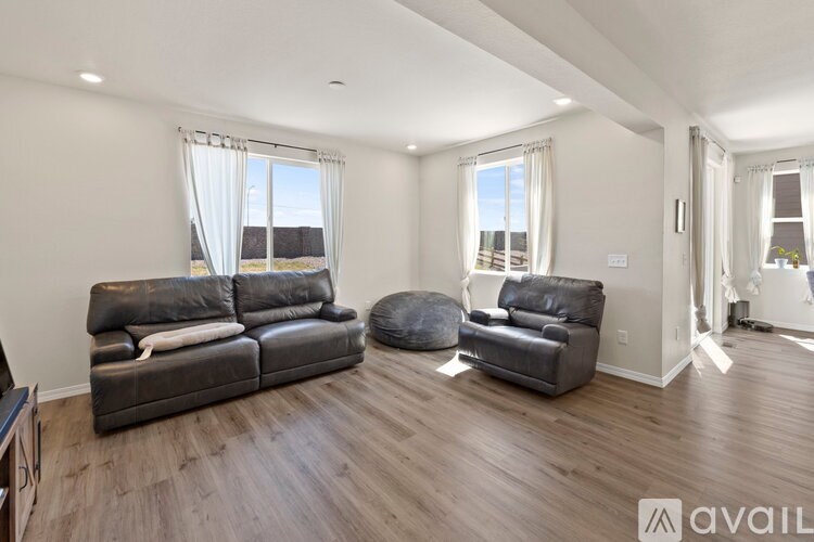 A living room with a large leather couch and ottoman.