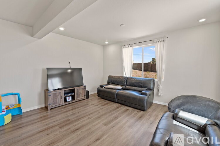 A living room with a flat screen TV and a black leather couch.