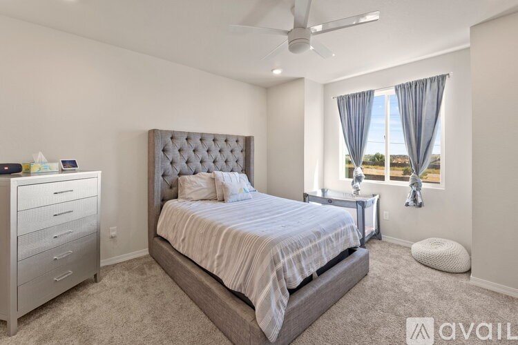 A bedroom with a large bed, a dresser, and a window with curtains.
