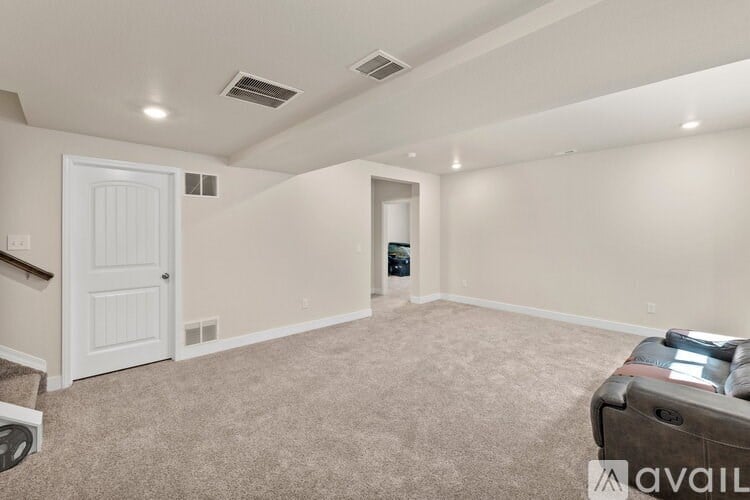 A spacious room with a carpeted floor and a white door.