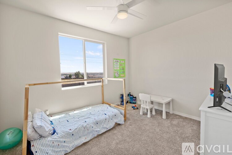 A bedroom with a bed, desk, and a window overlooking the landscape.