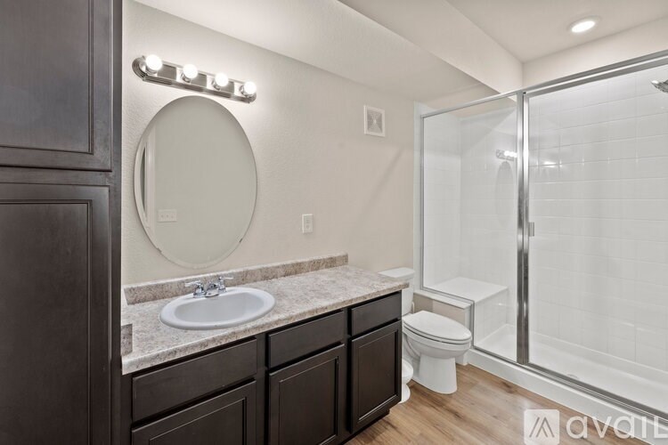 A bathroom with a sink, toilet, and mirror.