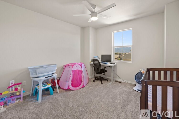 A room with a white chair, a pink tent, a desk with a computer, and a window with a view of the beach.