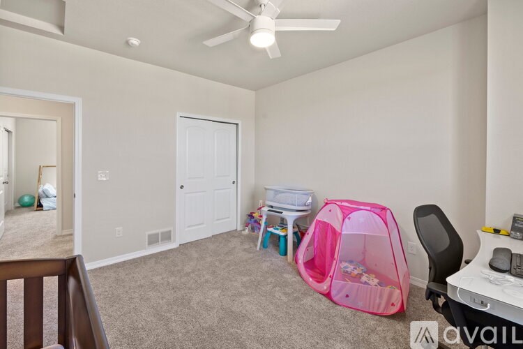 A room with a pink tent and a white table with a laptop on it.