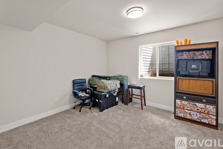 A room with a window, a chair, a desk, and a dresser with a floral design.