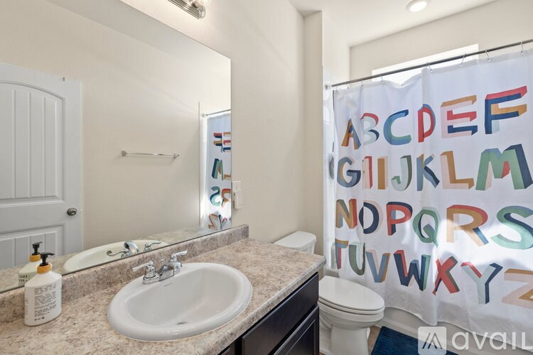 A bathroom with a white sink, toilet, and a shower curtain with letters on it.