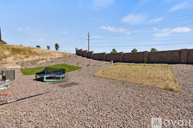 A gravel area with a fence and a blue object in the middle.
