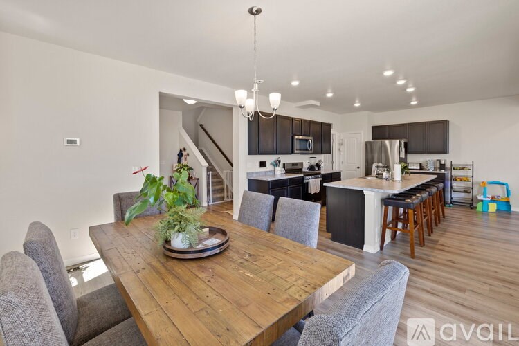A modern kitchen with a wooden dining table and grey chairs.