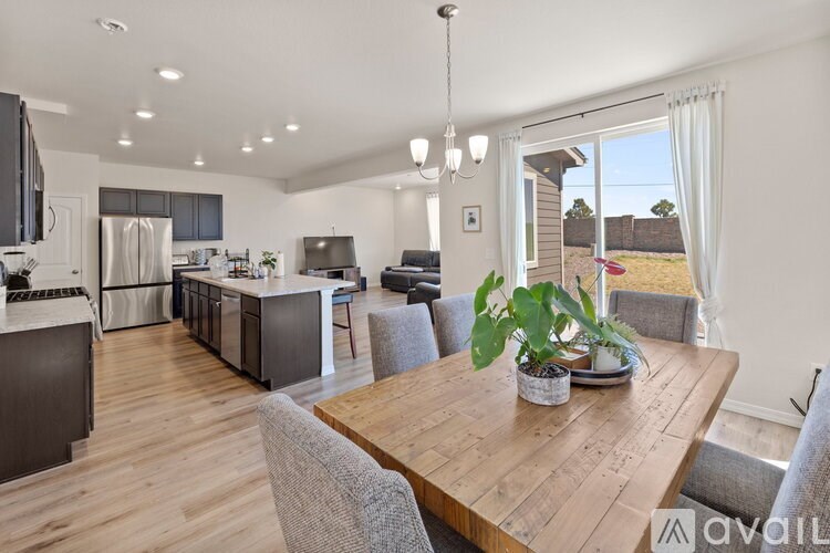 A modern kitchen with a wooden table and grey chairs.