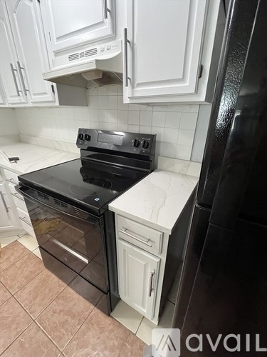 A black fridge sits next to a black stove in a kitchen.