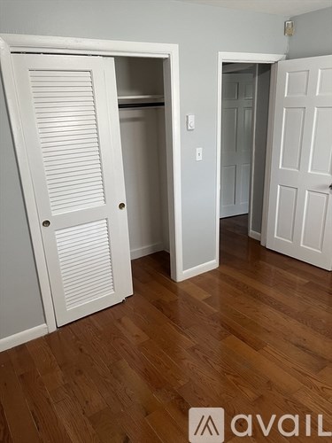 A room with a white door and a wooden floor.
