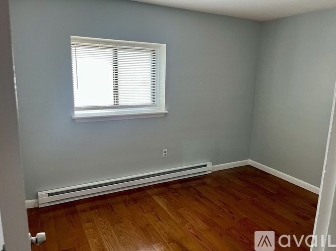 A room with wooden flooring and a window with blinds.