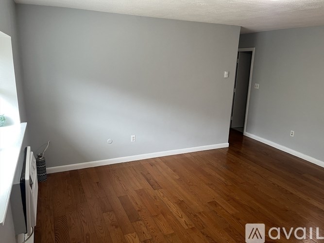 A room with wooden flooring and a window on the left side.